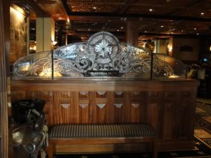 Wooden bench with decorative glass panel reading “The Driskill Hotel” inside a warmly lit interior.