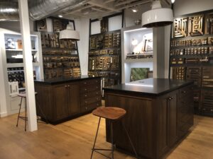 Showroom with wooden islands, stools, and wall displays of assorted hardware and fixtures under bright lighting.