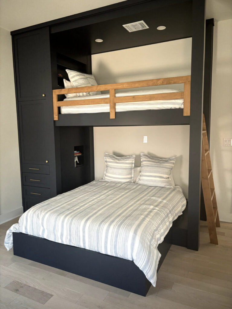 Modern bunk bed with a lower queen bed, upper twin bed, wooden ladder, and built-in storage on the left side.