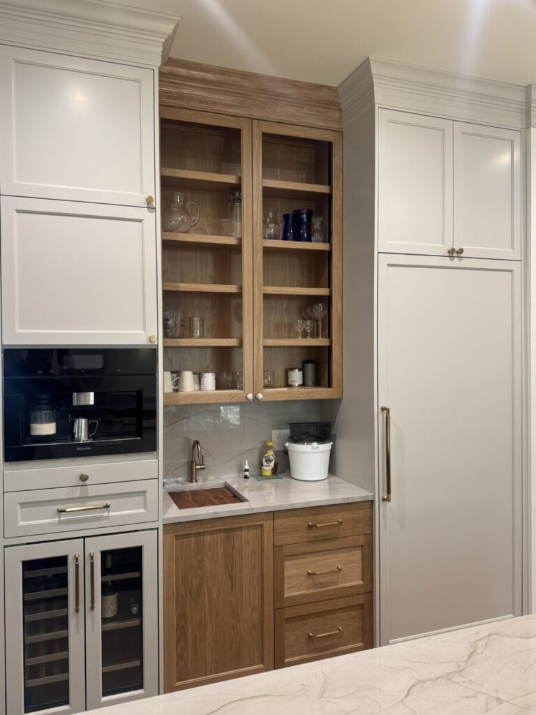 Modern kitchen with built-in appliances, open shelves with dishes, a small sink, and marble countertop.