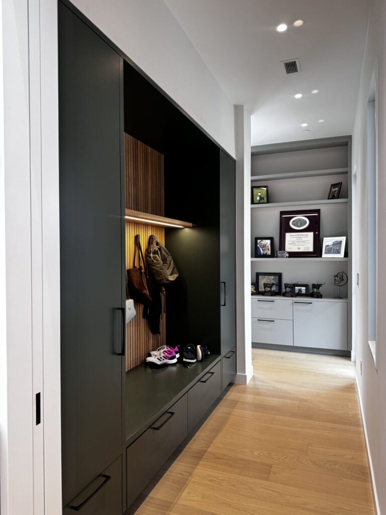 This modern hallway features built-in storage, display shelves with photos and awards, wood floors, and a minimalist design.