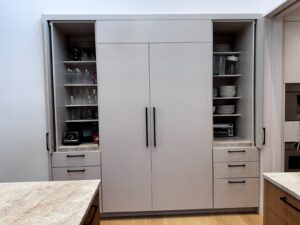 Open kitchen cabinets display glassware, dishes, a toaster oven, blender, coffee maker, and various small appliances.