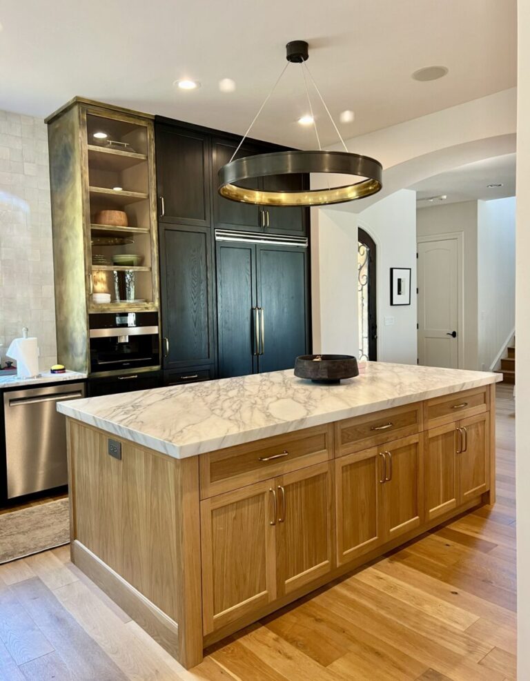 Modern kitchen with a marble island, wooden cabinets, black appliances, and a circular pendant light.